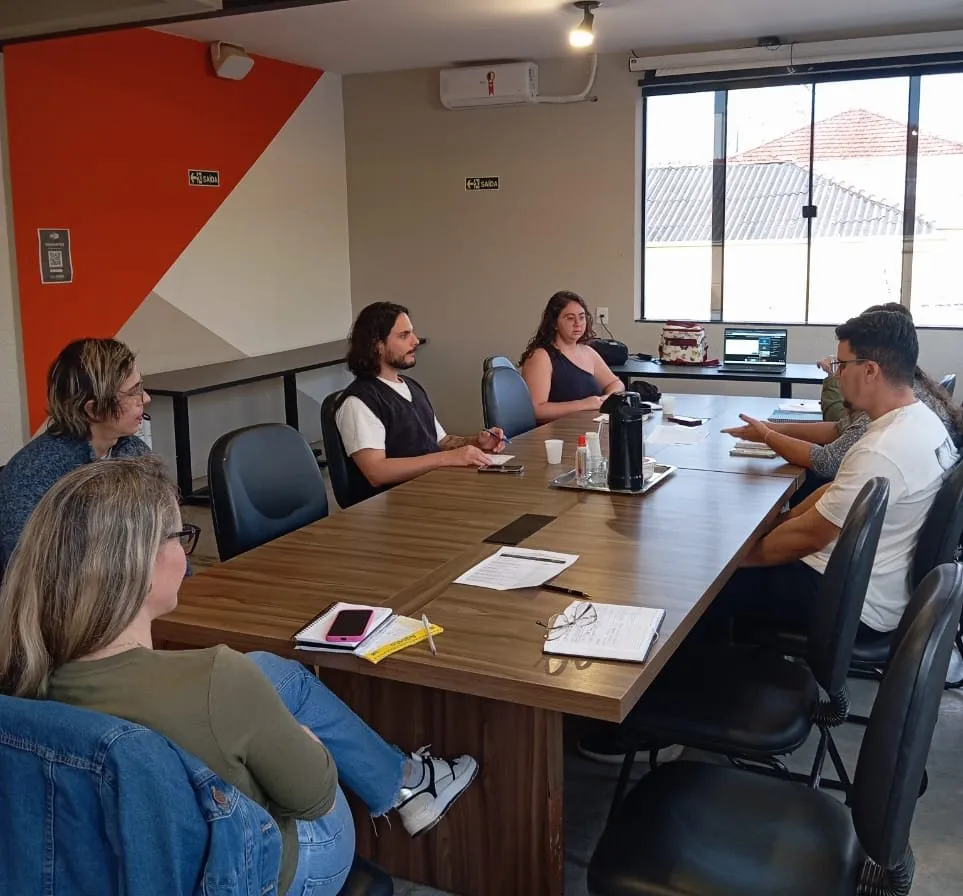 Reunião ao redor de uma mesa, com Gabriel Meyer entre os participantes