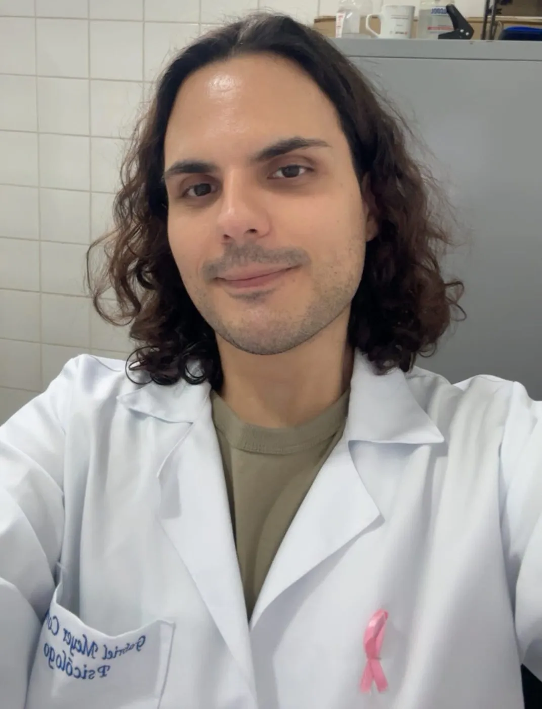 Gabriel Meyer de jaleco branco, com um laço rosa no peito